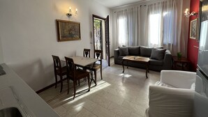A living room with a dining table, chairs, a sofa, and a coffee table.
