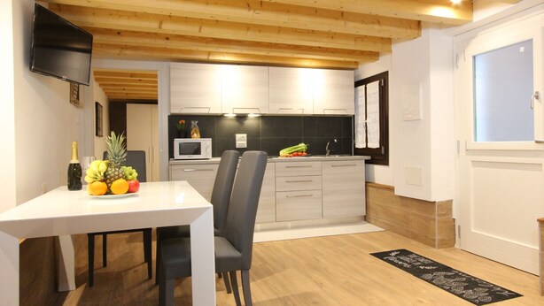 A modern kitchen with white cabinets, a microwave, and a fruit bowl on the counter. - Apt. Ca'Puccetti Bis (350mt from Rialto's Bridge) (Venecia)