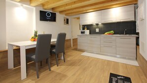 A modern kitchen with white cabinets, a wooden ceiling, and a dining area with a white table and chairs. - Apt. Ca'Puccetti Bis (350mt from Rialto's Bridge) (Venecia)
