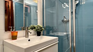 A bathroom with a white sink, a mirror, a potted plant, and a shower area with blue tiles. - Gondola Grand Canal (Historical Center) (Venecia)