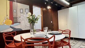 A dining area with a round table set for four, surrounded by red chairs. A vase with white flowers is on the table. - Gondola Grand Canal (Historical Center) (Venecia)