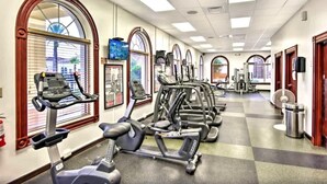 Un gimnasio con cintas de correr, elípticas y equipo de pesas.