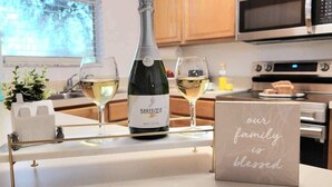 Una encimera de cocina con una botella de Barefoot Brut Chablis, dos copas de vino y un letrero que dice 'nuestra familia es bendecida'.