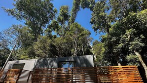 A modern RV with a grey exterior, wooden benches, and a staircase leading to the entrance. - Recanto das Videiras - container (Itapira)