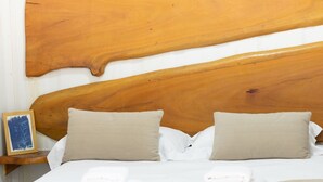 A hotel room with a wooden headboard, two beige pillows, a neatly made bed with white linens, and a framed picture on the nightstand. - Recanto das Videiras - container (Itapira)
