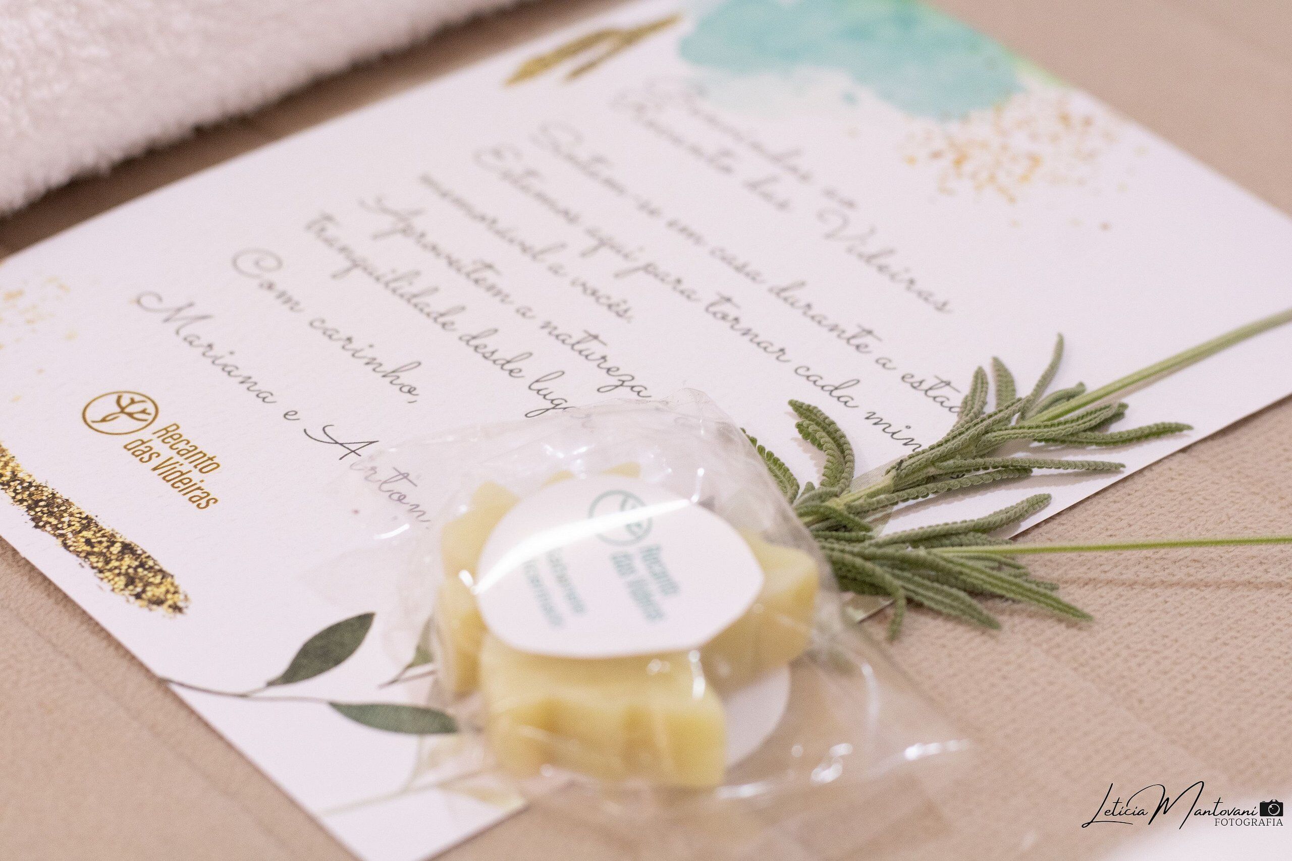 Una invitación de boda con una ramita de romero y un pequeño objeto envasado, posiblemente un regalo o adorno.