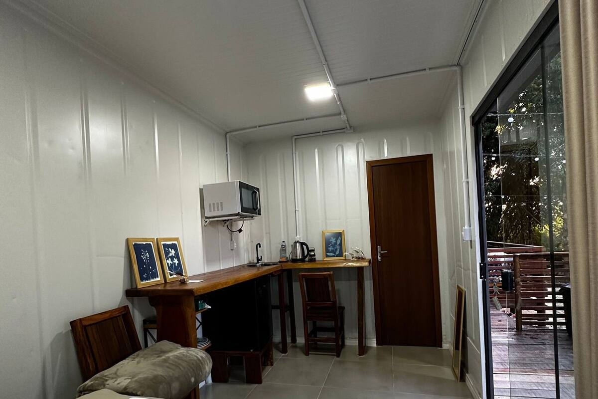 A compact bedroom with a bed, a desk, and a small kitchenette.