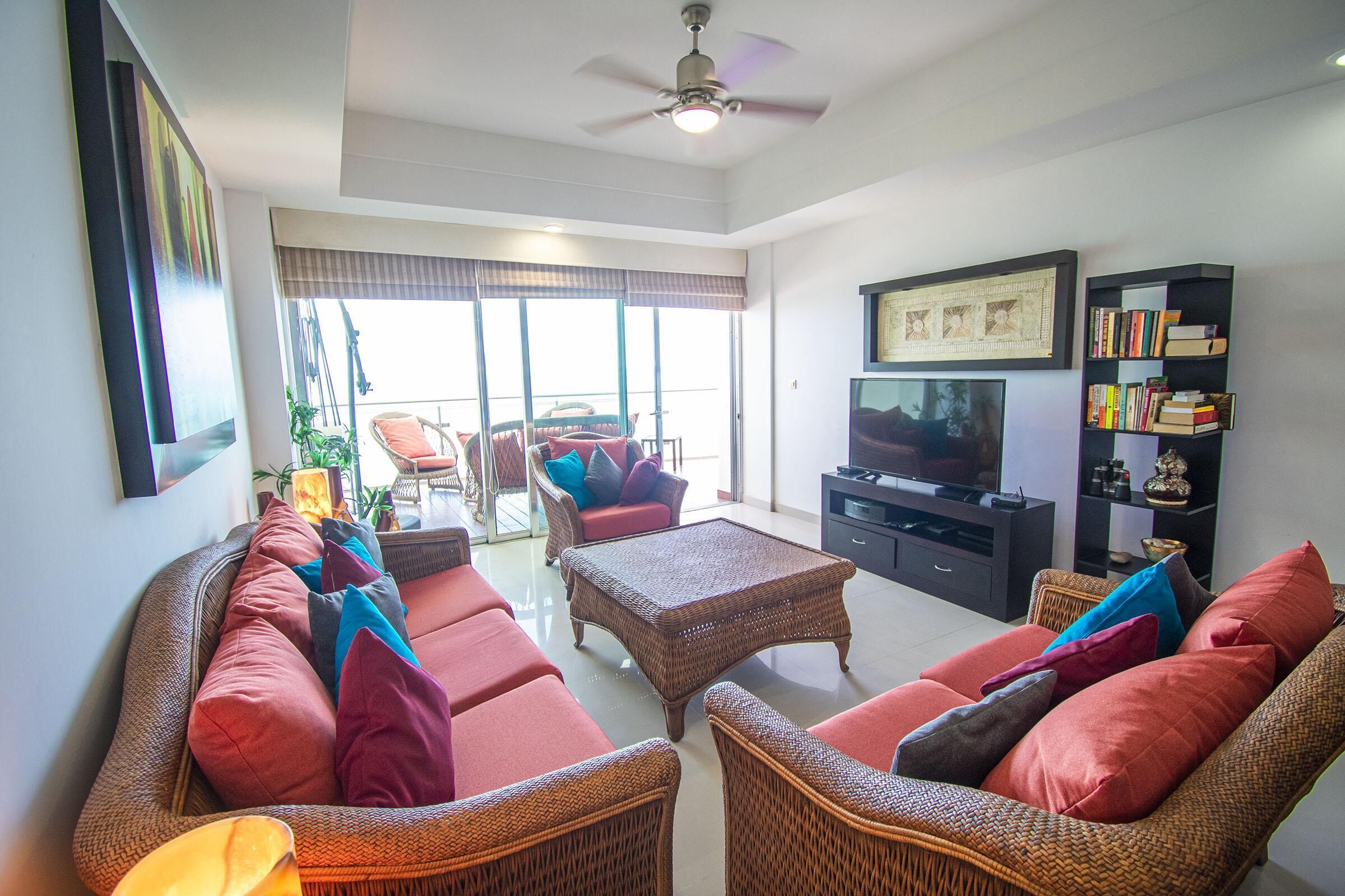 A living room with a sofa set, a coffee table, a television, and a bookshelf.