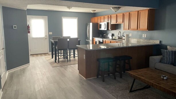 Une cuisine moderne avec des meubles en bois, un îlot central et un coin repas comprenant une table et des chaises.