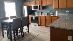 Une cuisine moderne avec des meubles en bois, des appareils en acier inoxydable et un plan de travail en granit.