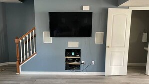 A room with a mounted TV, a white door, and a staircase. - Luxury Townhome #2  - Remodeled Feb 2021 (Bloomington)