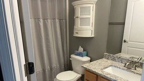 A bathroom with a toilet, a sink with a granite countertop, and a cabinet above the toilet. - Luxury Townhome #2  - Remodeled Feb 2021 (Bloomington)