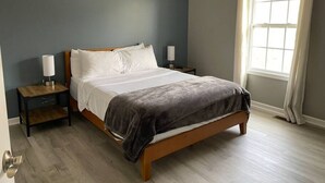 A bedroom with a bed, nightstands, a lamp, and a window with curtains. - Luxury Townhome #2  - Remodeled Feb 2021 (Bloomington)