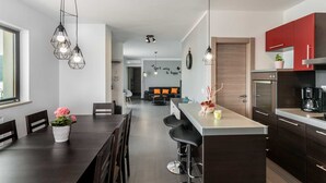 Una cocina moderna con armarios oscuros, una isla central e iluminación colgante.
