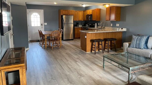 A modern kitchen with wooden cabinets, a stainless steel refrigerator, and a central island with stools.