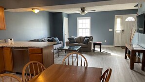 A spacious living area with a kitchen, dining table, and seating.