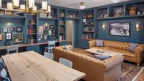 A cozy living room with a wooden coffee table, a brown leather sofa, and a bookshelf filled with books and decorative items. - Hotel Ursa (Orono)
