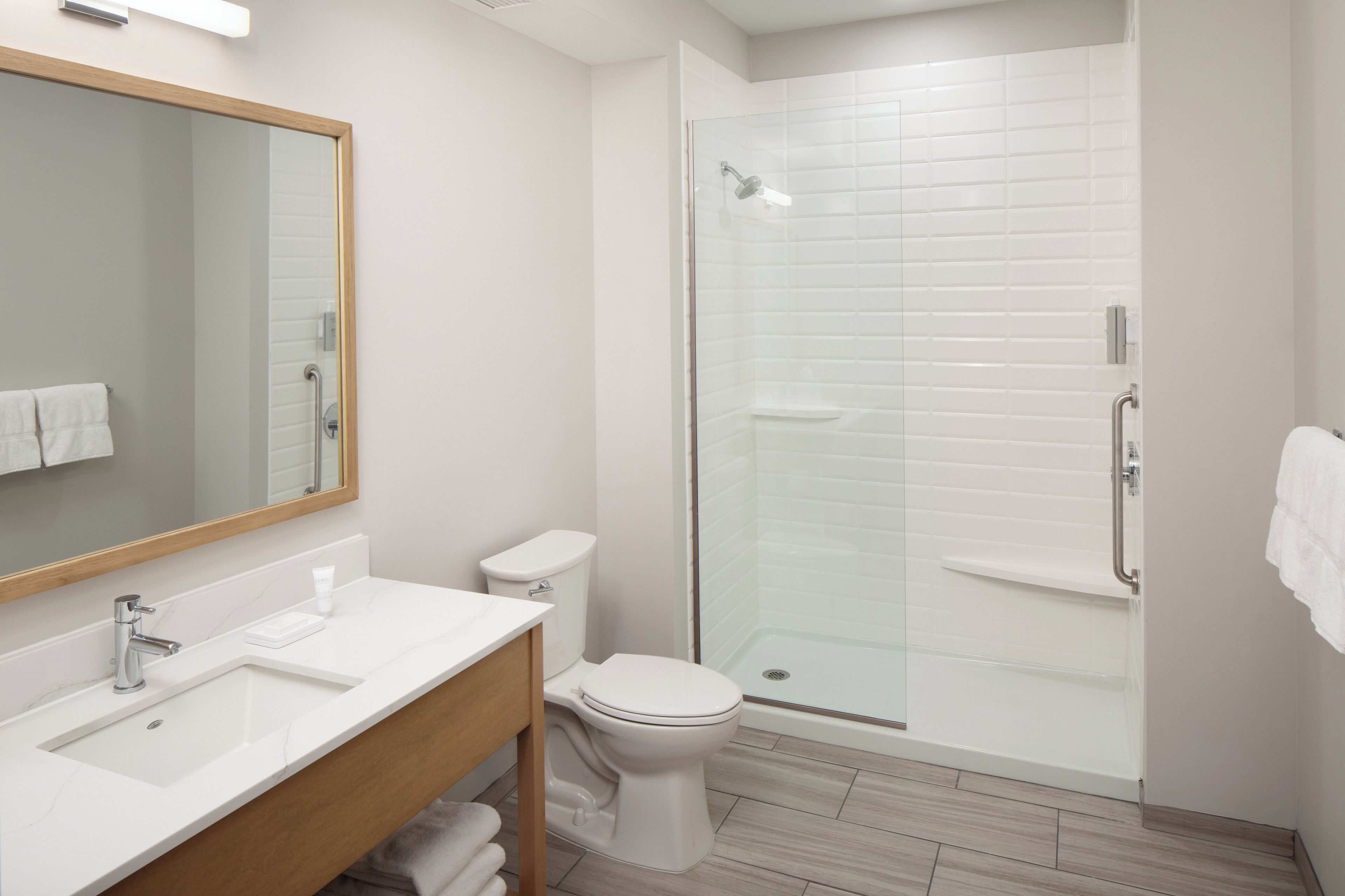 Un baño moderno con ducha de vidrio, lavamanos blanco y retrete.