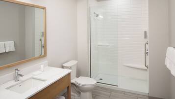 Un baño moderno con ducha de vidrio, lavamanos blanco y retrete.