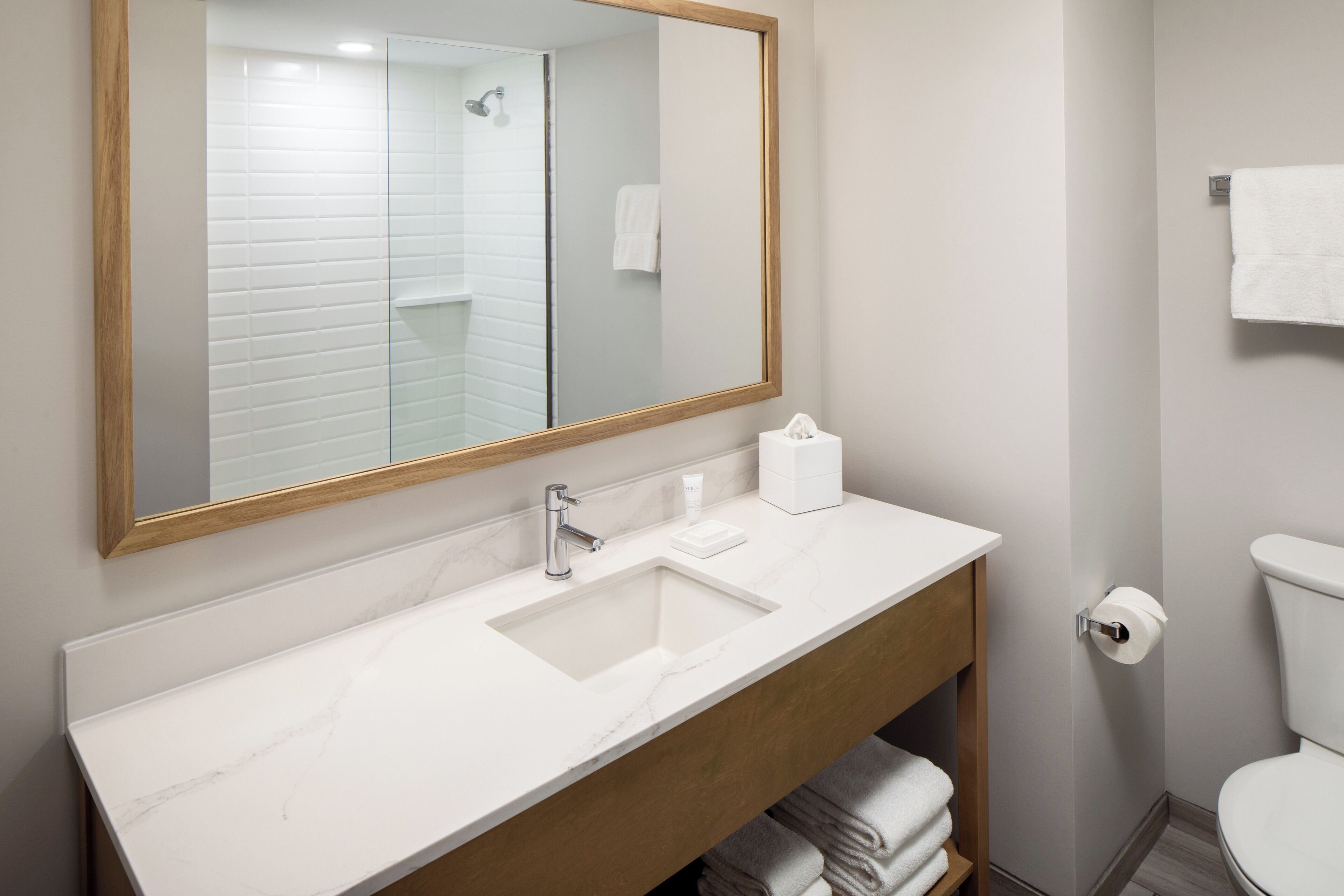 A bathroom with a white sink, a mirror, a toilet, and a towel rack.