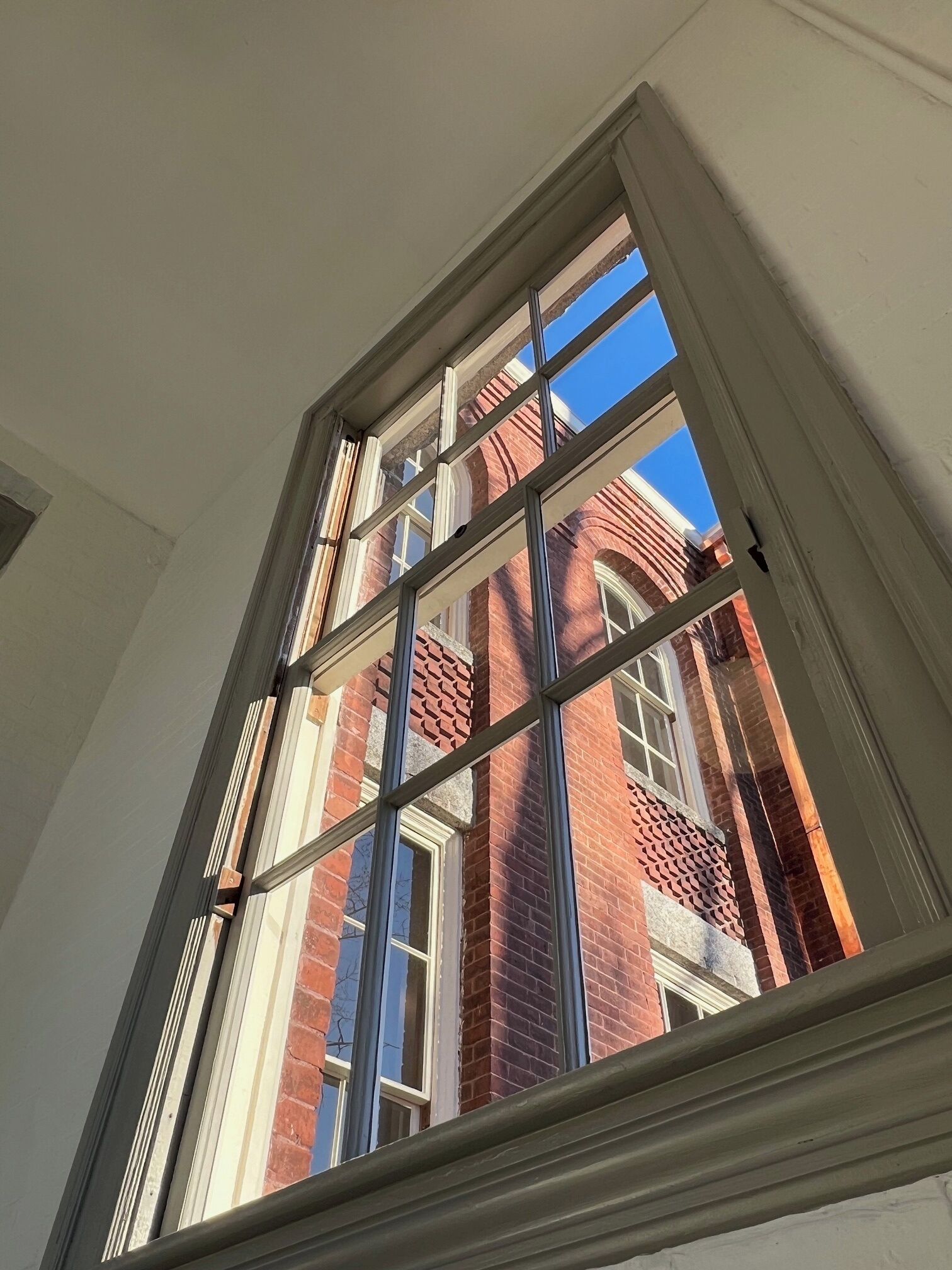 A window with a view of a red brick building.