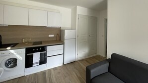 Une cuisine compacte équipée d’un lave-linge, d’un four et d’un réfrigérateur.