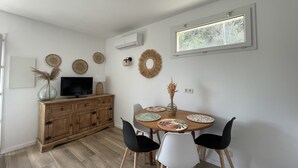 Un coin repas comprenant un buffet en bois, un téléviseur et une table ronde avec des chaises.