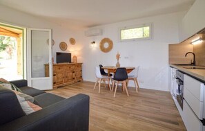 Cozy living space with a sofa, dining table, and TV, featuring a kitchen area with sink, stove, and oven.