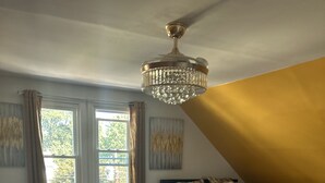 A bedroom with a bed, a heater, a window, and a chandelier.