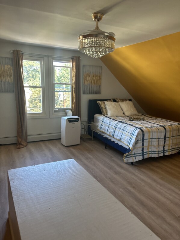 A bedroom with a bed, a heater, a window, and a chandelier. - Studio Apt with kitchen,Living room, bathroom & bedroom, near Griffith hospital (Ansonia)