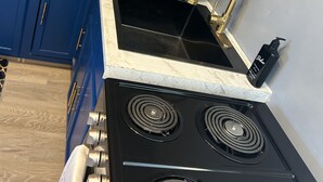 A kitchen with a black stove, blue cabinets, and a marble countertop.
