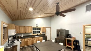 Une cuisine moderne avec des meubles en bois, une grande table à manger et un ventilateur de plafond.