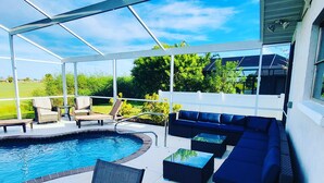 A covered outdoor area with a pool, seating, and a view of the surrounding landscape.