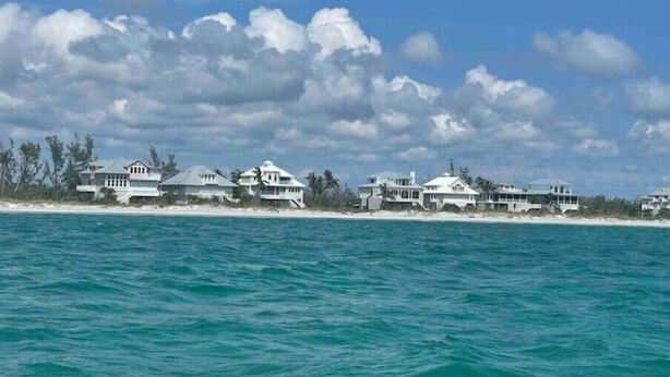 A coastal property with multiple white buildings, a sandy beach, and a view of the ocean.