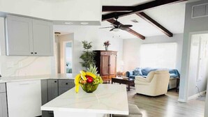 A modern kitchen with a central island, grey cabinets, and a ceiling fan.