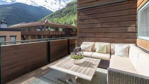A balcony with a wooden floor, a sofa with cushions, and a potted plant. - So Close to Skiing at Sunny Ice House! Parking, Pool, Hot Tub (Telluride)