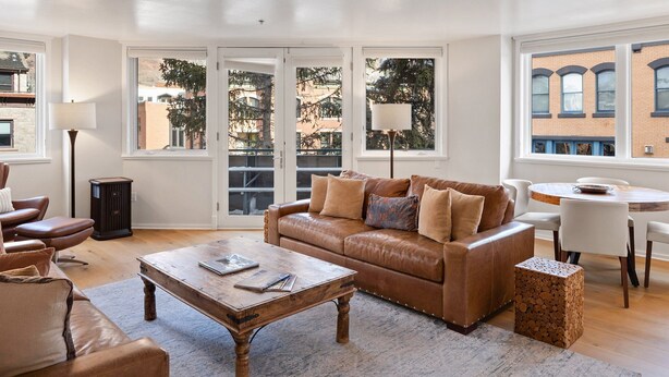 A living room with a brown leather sofa, a wooden coffee table, and a dining table with chairs. - So Close to Skiing at Sunny Ice House! Parking, Pool, Hot Tub (Telluride)