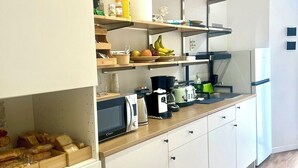 A compact kitchen with white cabinets, a microwave, a toaster, and a coffee maker on the countertop. - Lexie Suites Guesthouse (Rome)