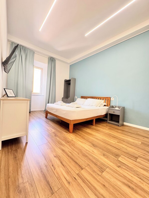 A bedroom with a bed, bedside table, nightstand, and a wardrobe. - Lexie Suites Guesthouse (Rome)