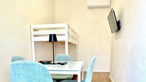 A bunk bed with a desk and chairs, a lamp, and a TV on the wall. - Lexie Suites Guesthouse (Rome)