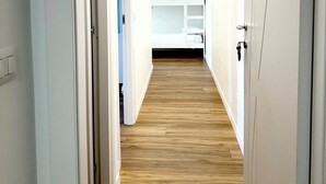A narrow hallway with wooden flooring, white walls, and a bunk bed in the distance. - Lexie Suites Guesthouse (Rome)