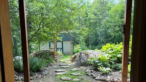 A stone pathway leading to a wooden pergola with a view of a garden and a shed. - Charming 3,800 sq feet log house in Waupaca County.  (Ogdensburg)