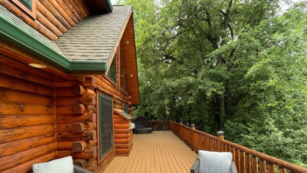 A wooden cabin with a deck, wicker furniture, and a barbecue grill. - Charming 3,800 sq feet log house in Waupaca County.  (Ogdensburg)
