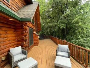 A wooden cabin with a deck, wicker furniture, and a barbecue grill. - Charming 3,800 sq feet log house in Waupaca County. (Ogdensburg)
