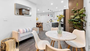 A modern living room with a sofa, a dining table with chairs, a kitchen in the background, and a large mirror on the wall. - Upscale Resort House /Views, Saltwater Pool/Spa !
 (Spring Valley)