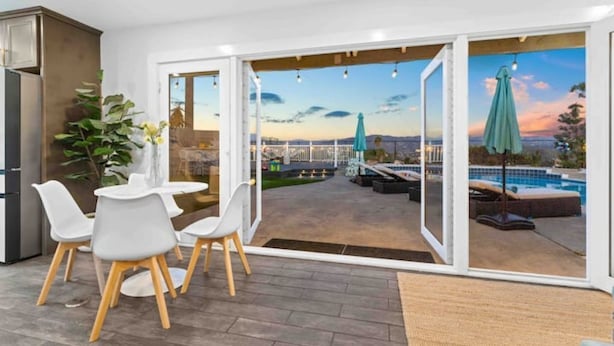 A modern room with a dining area, a view of a swimming pool, and a large sliding glass door leading to an outdoor patio. - Upscale Resort House /Views, Saltwater Pool/Spa !
 (Spring Valley)
