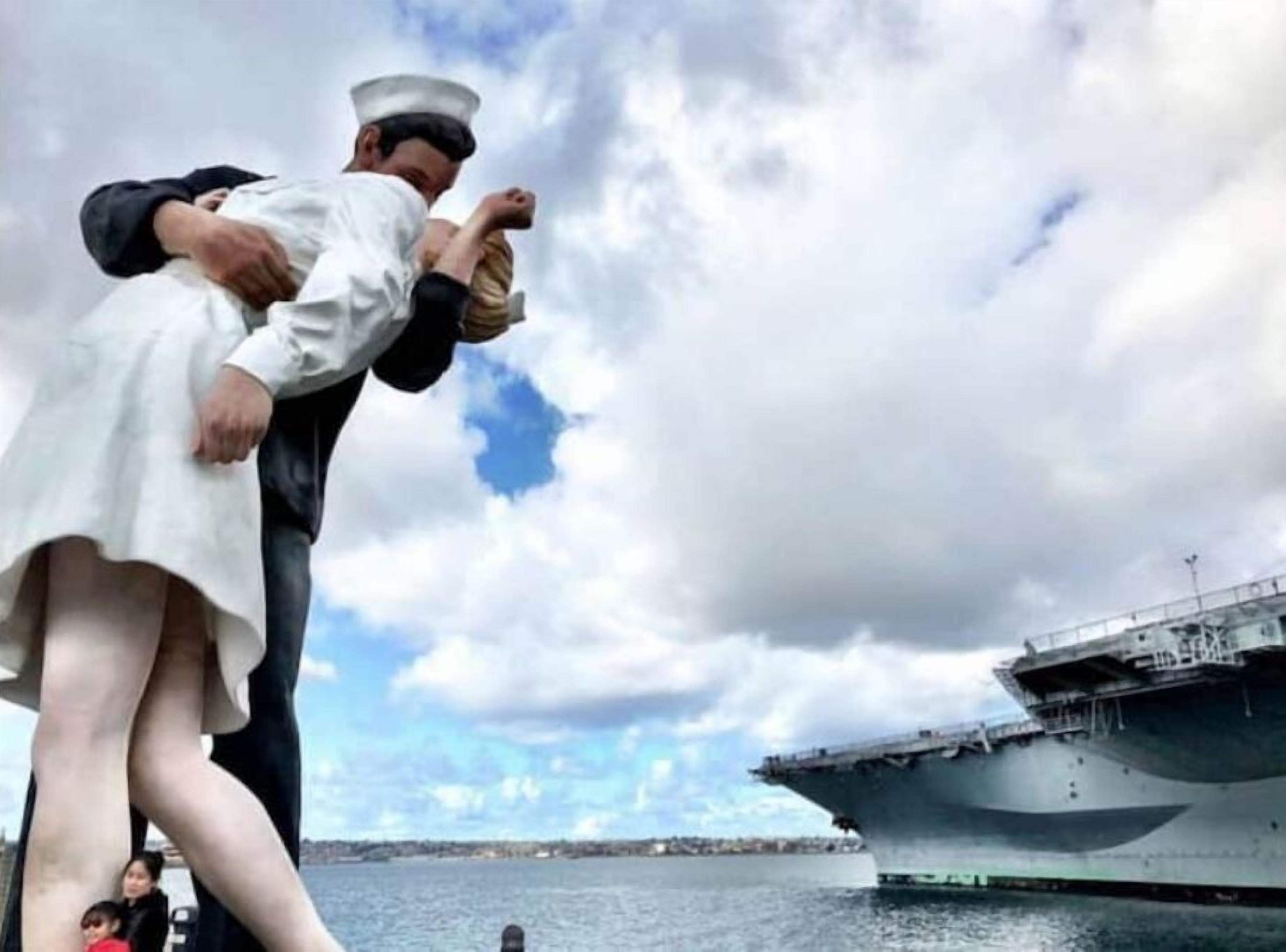 A person in a white dress and sailor hat embracing another person on a ship deck.