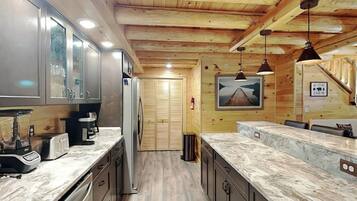 A modern kitchen with wooden ceiling beams, granite countertops, and stainless steel appliances.