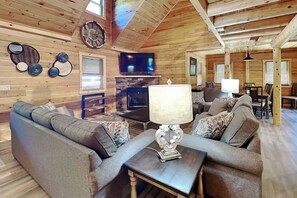 A cozy cabin interior with a fireplace, a television, and a dining area. - Alpine Valley by Taylor Made Deep Creek (McHenry)
