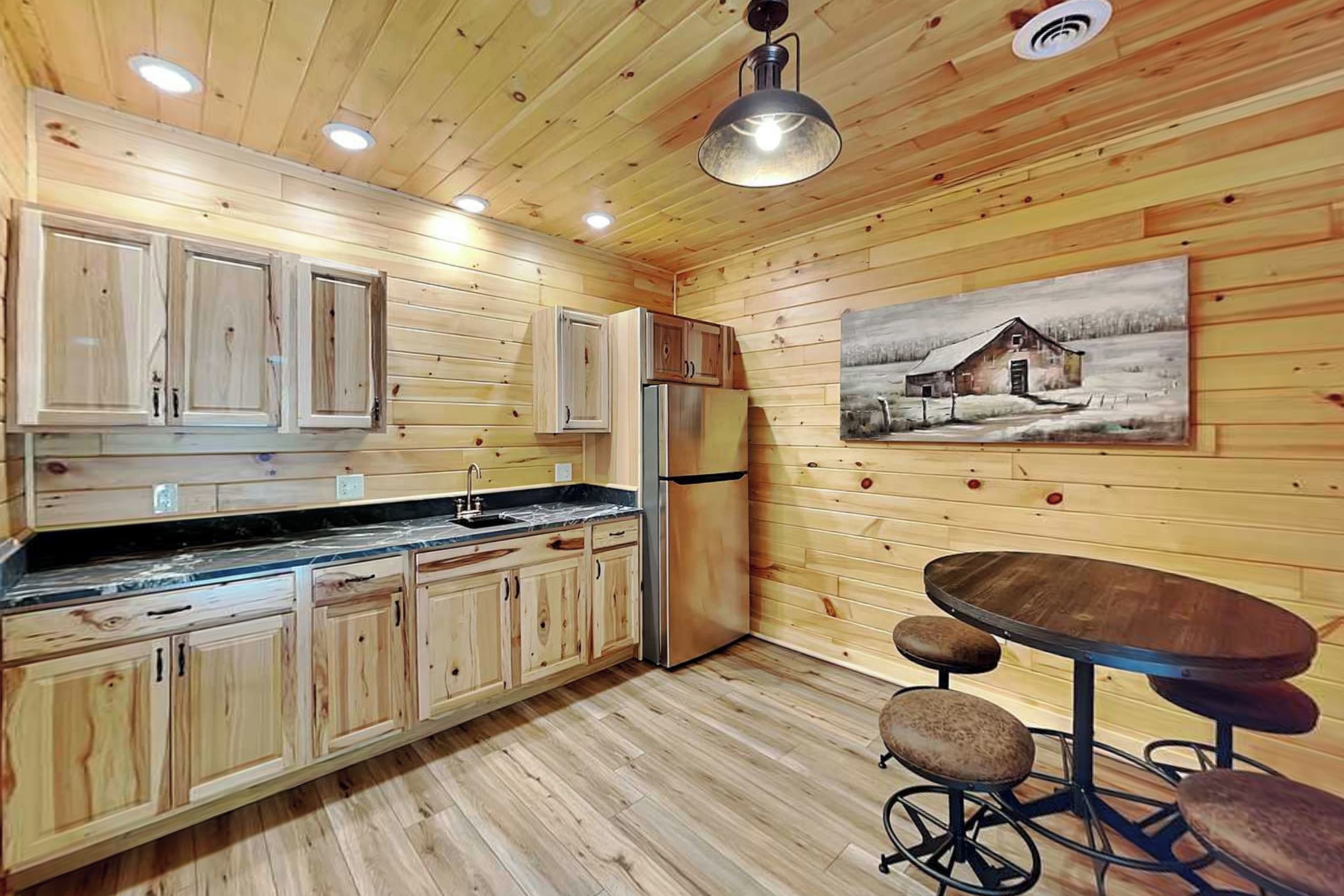 A wooden interior with a kitchen, dining area, and a painting on the wall.